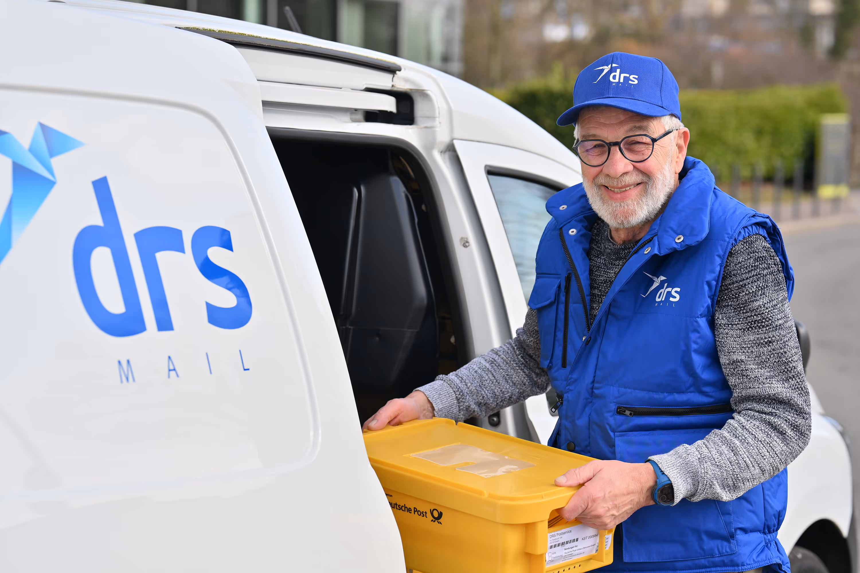 Fahrer von drs Mail lädt eine Postkiste in den Transporter
